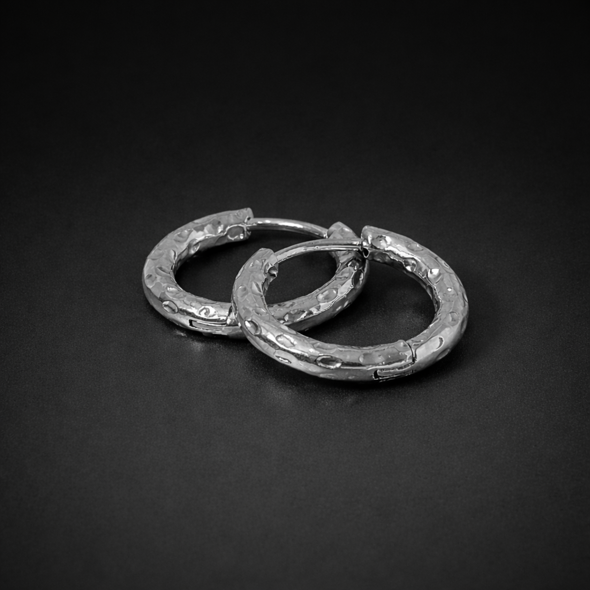 Close up of the silver waterproof Aura Hoops, size 12mm, on a black surface