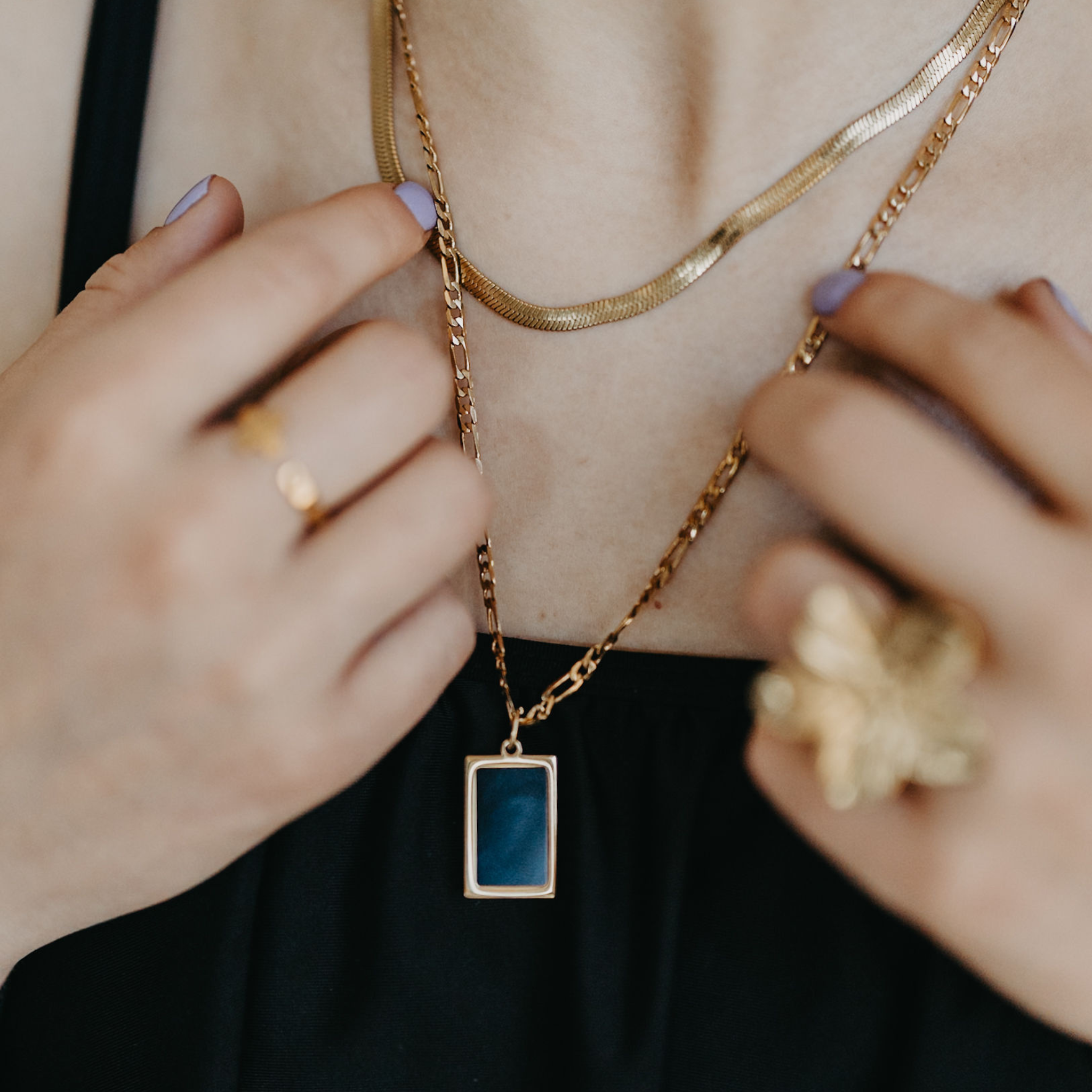 model wearing Eclipse herringbone necklace layered with gold pendant necklace and waterproof jewelry