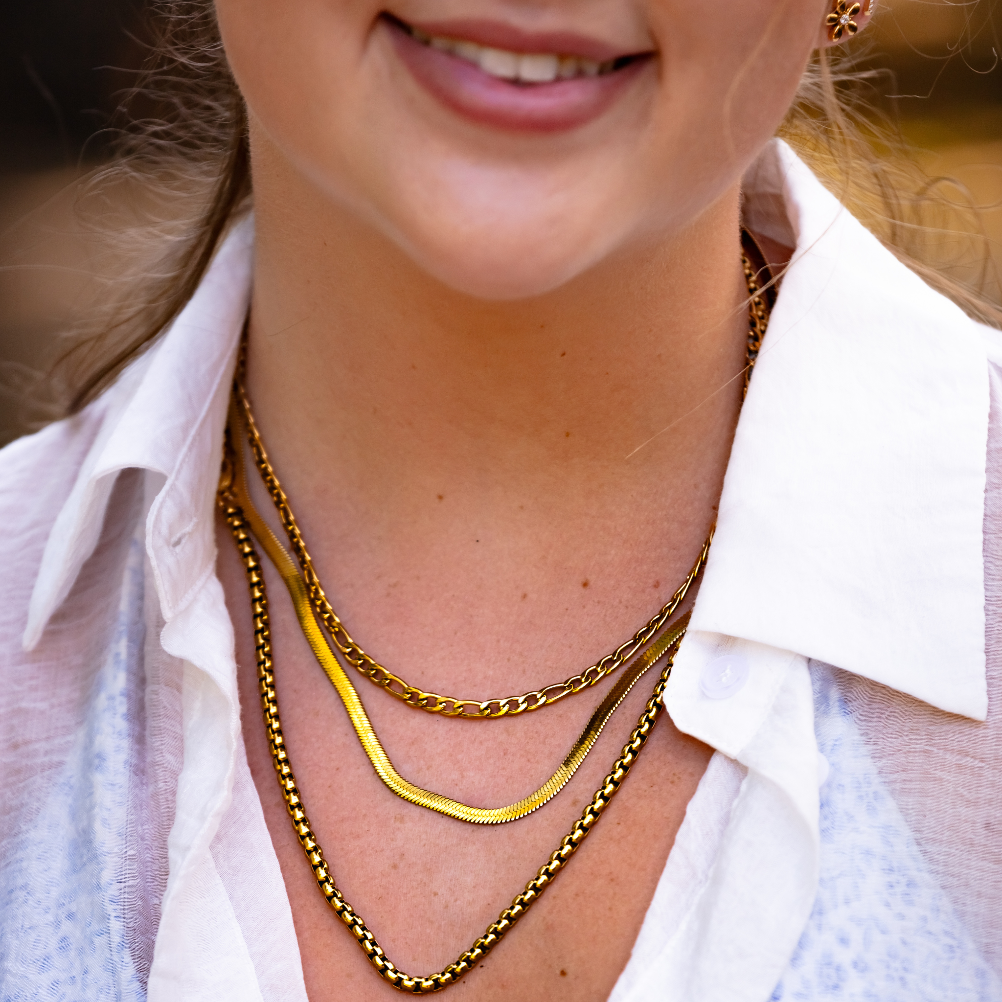close up of Forge figaro chain necklace layered with gold waterproof chains and herringbone necklace