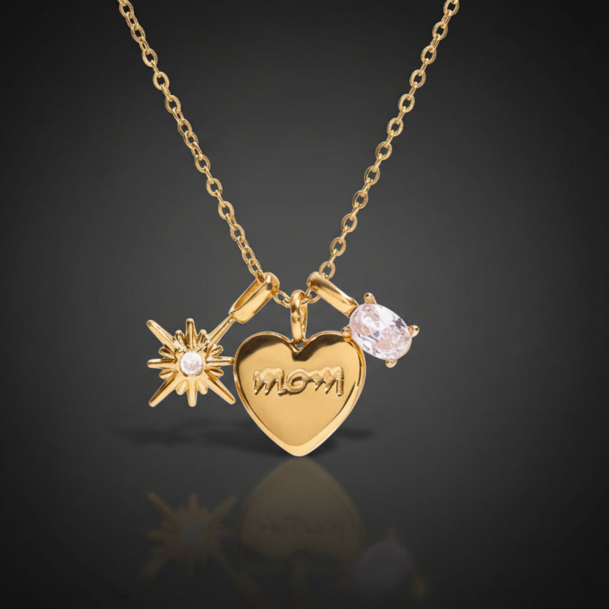 18K gold PVD Mom Moments necklace on dark background with heart charm engraved mom, starburst charm, and oval cubic zirconia stone