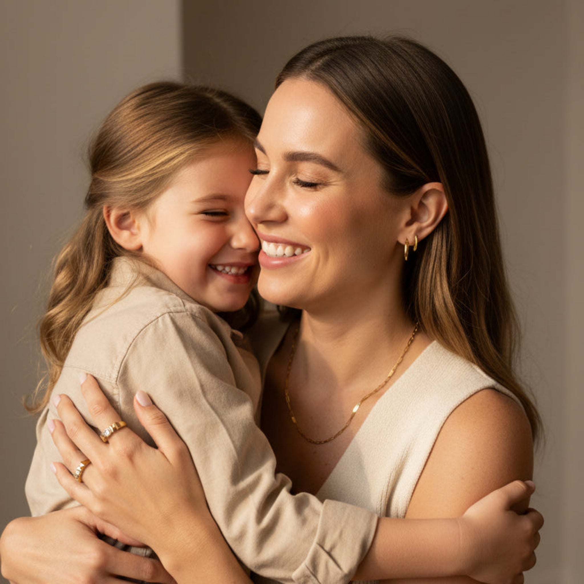 Mother and daughter embracing while wearing Mom Signature Set gold jewelry, waterproof 18K gold PVD necklace, earrings, and ring gift for Mother’s Day