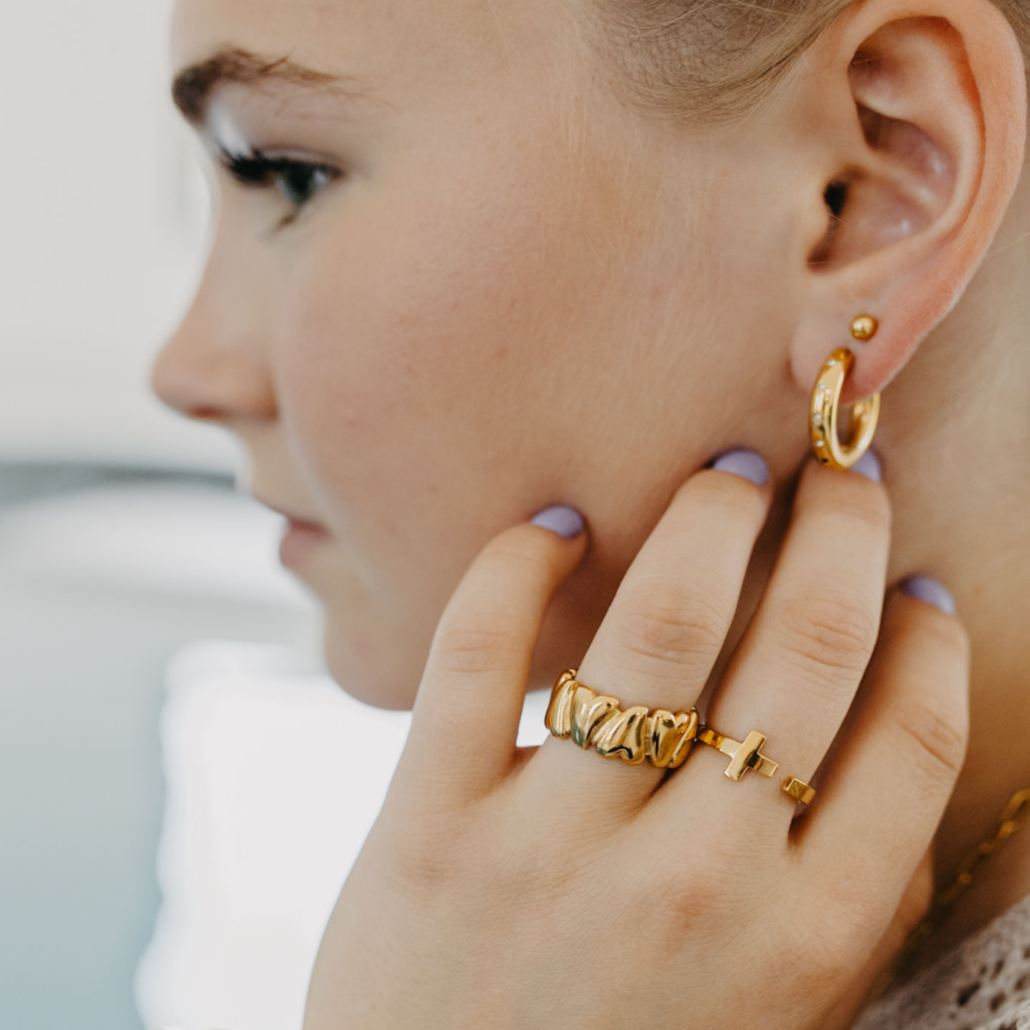 Close-up of young woman wearing adjustable waterproof silver heart ring with matching earrings