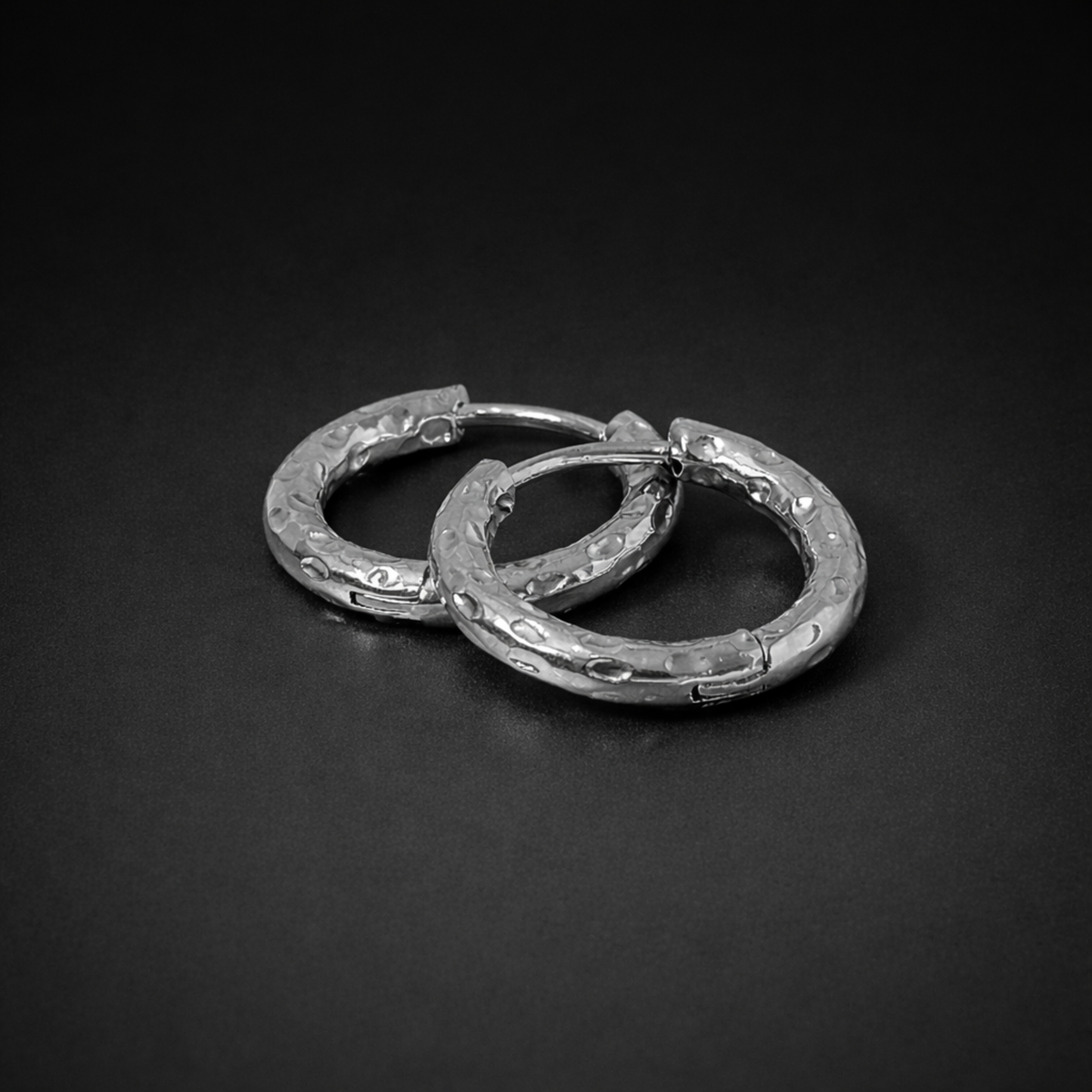 Close up of the silver  waterproof Aura Hoops, size 12mm, on a black surface