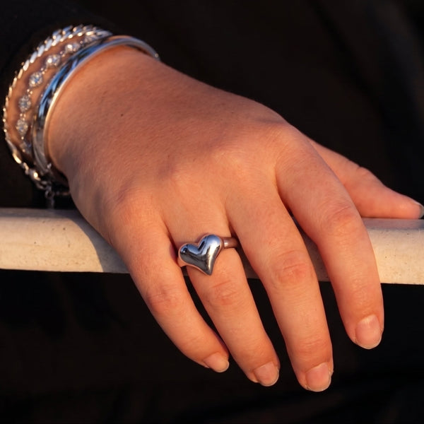 Close-up of a hand wearing the silver Depths of Love Heart Ring with bracelets.