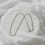 Eclipse herringbone necklace in silver stainless steel displayed on soft white fabric waterproof jewelry 5