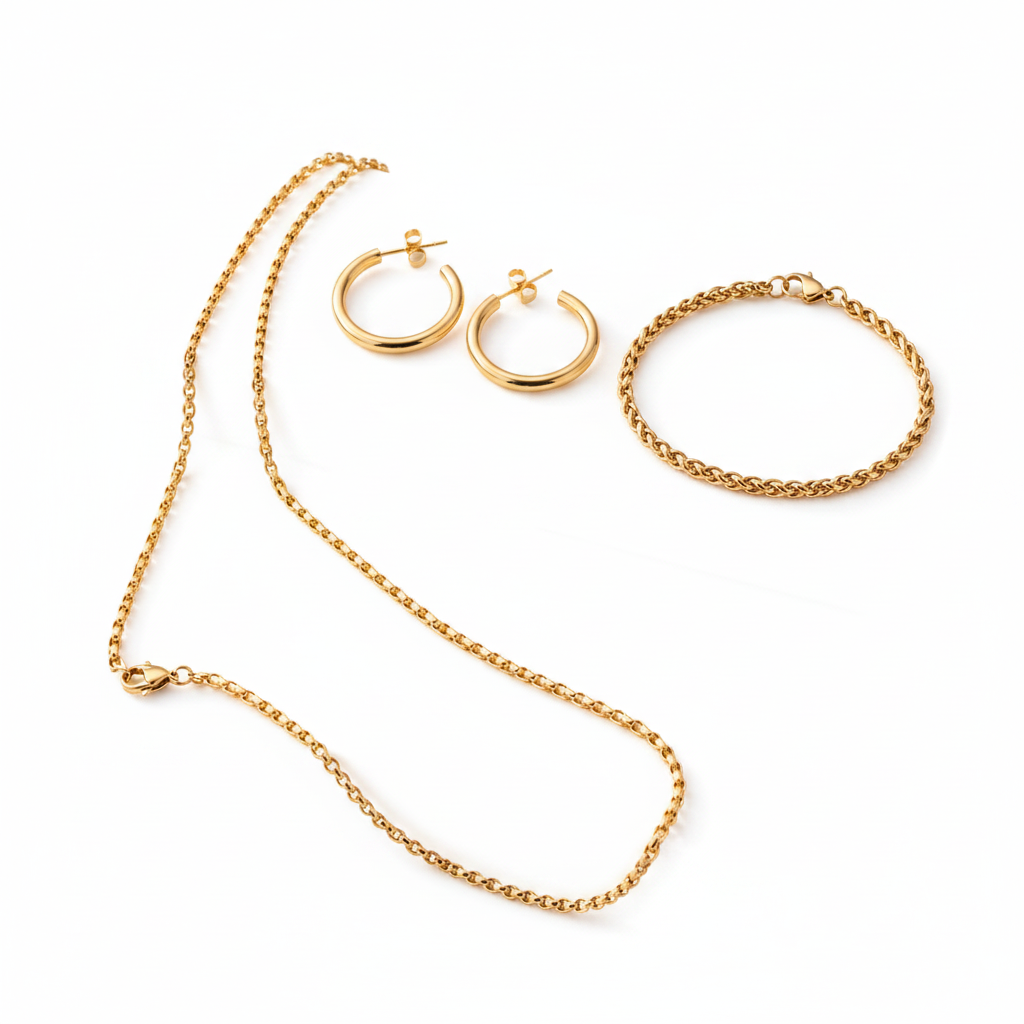 Essential Set jewelry featuring 18K gold PVD waterproof necklace, bracelet and hoop earrings displayed on soft pink blocks, tarnish resistant gold jewelry set