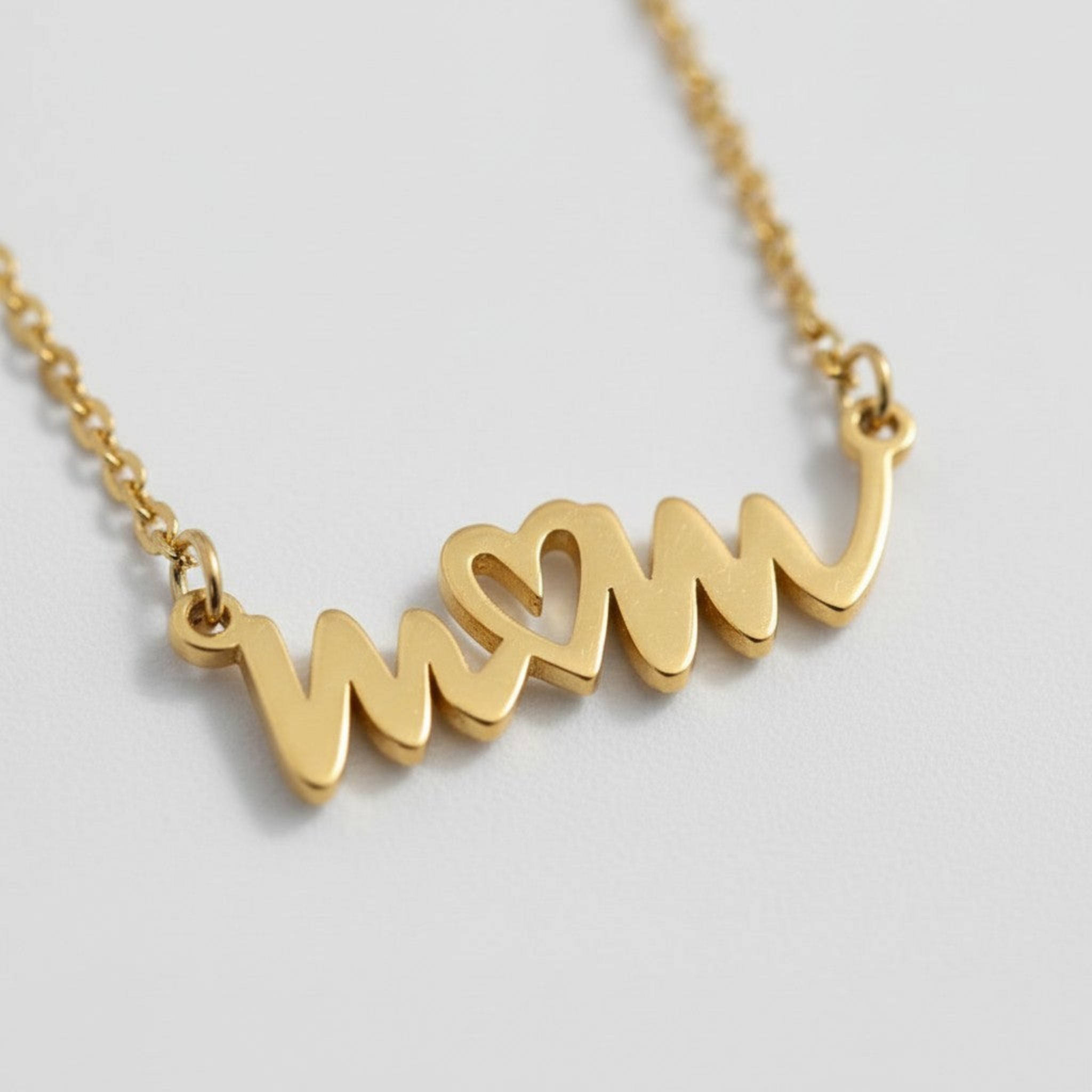 close-up of handwritten style mom necklace in 18K gold PVD with heart detail on fine chain