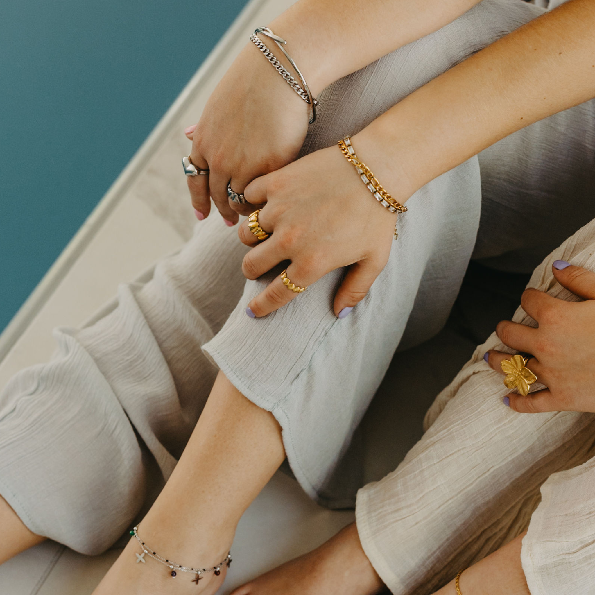 models wearing Forge figaro chain bracelets layered with gold and silver waterproof jewelry