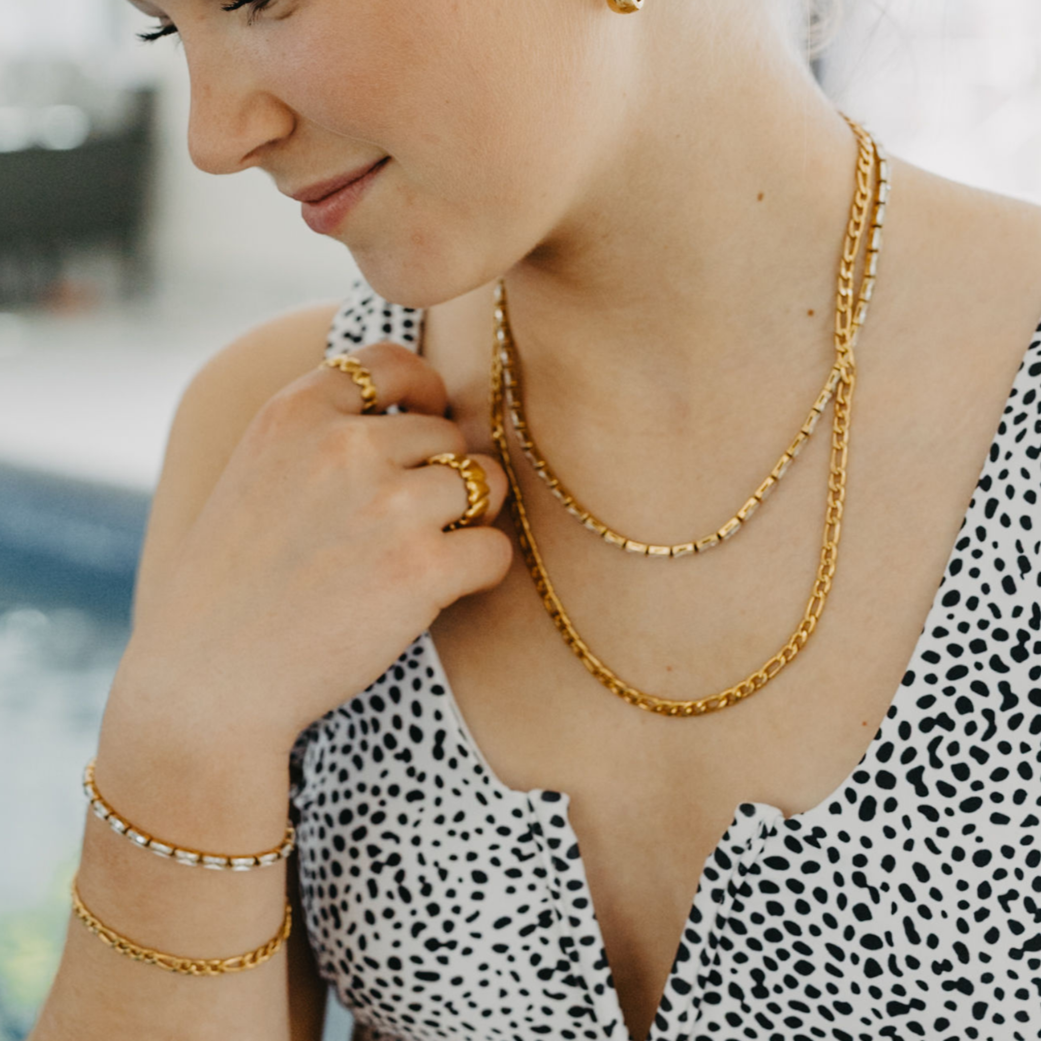 model wearing Forge figaro chain necklace and bracelet layered with 18K gold PVD waterproof jewelry