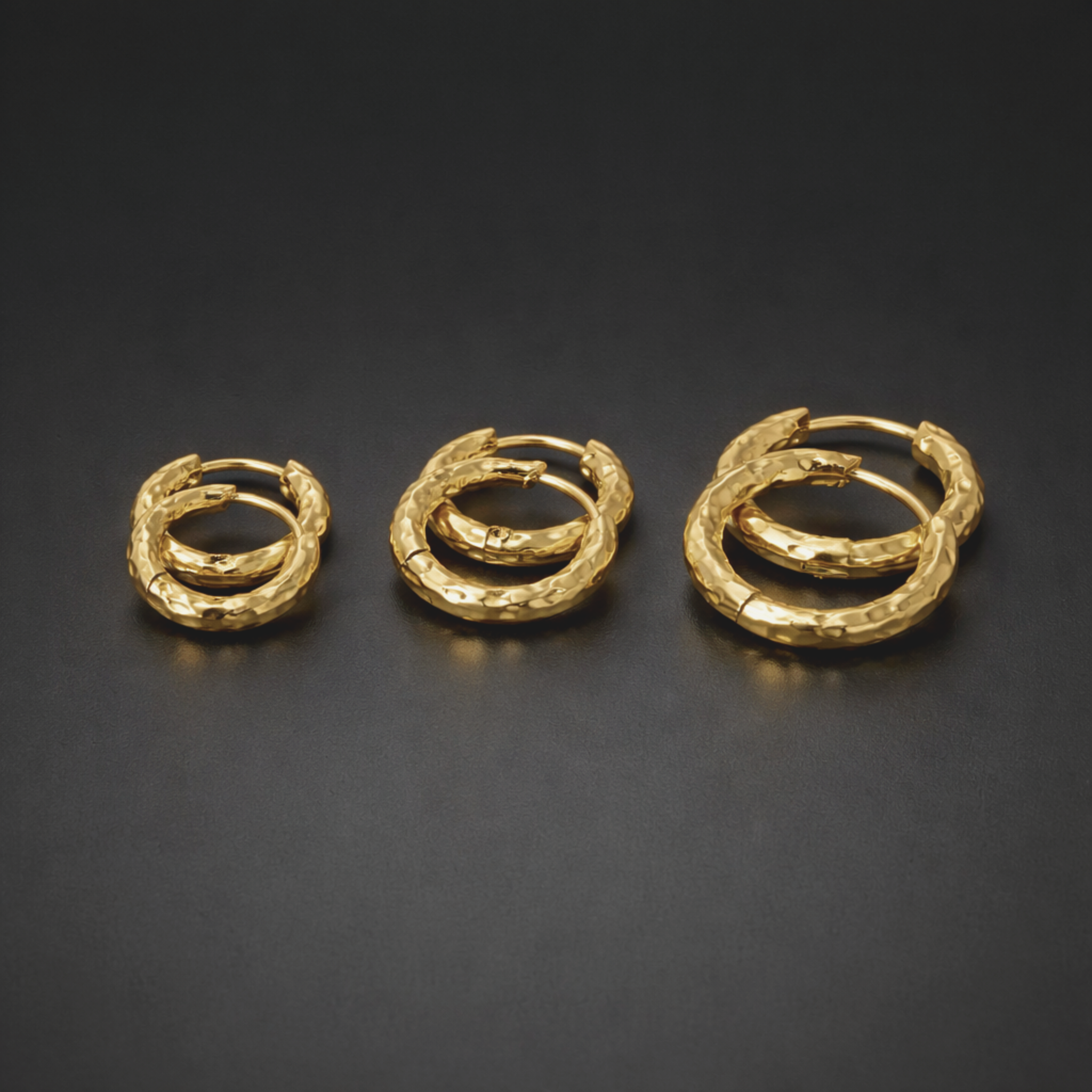 Three pairs of gold hoop earrings side by side, in size 8mm, 10mm and 12mm on a black background