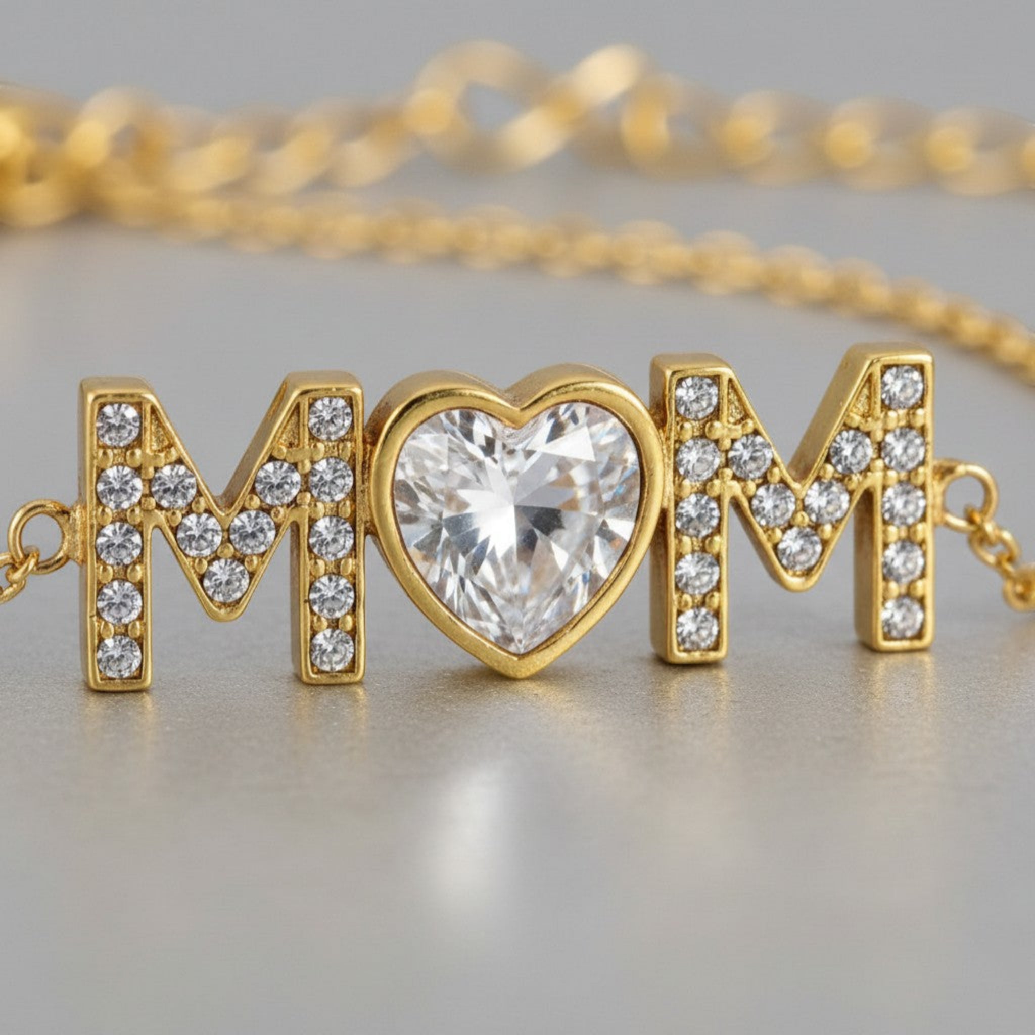 Close-up of Mom Radiance bracelet showing pavé cubic zirconia letters and heart shaped center stone in 18K gold PVD finish