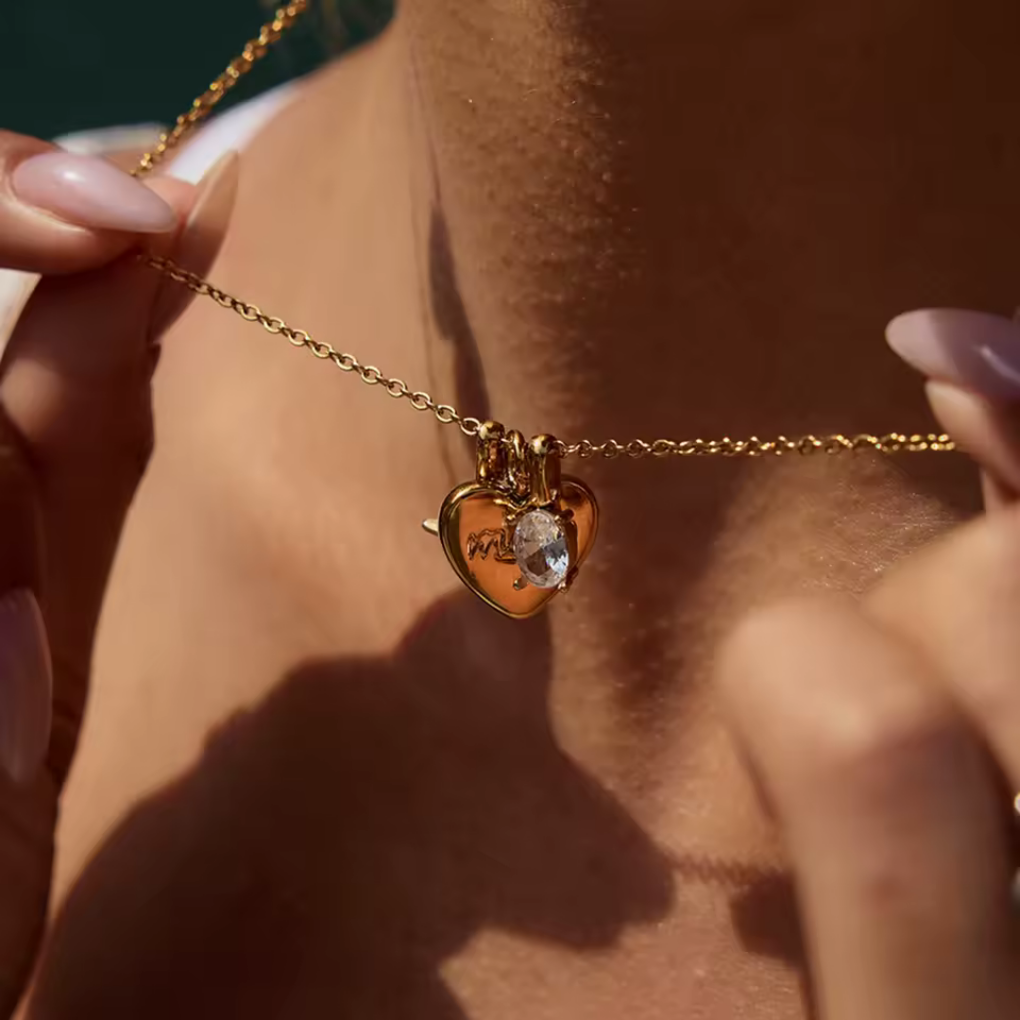 woman wearing Mom Moments gold heart pendant necklace with engraved mom charm, starburst detail, and sparkling oval cubic zirconia stone